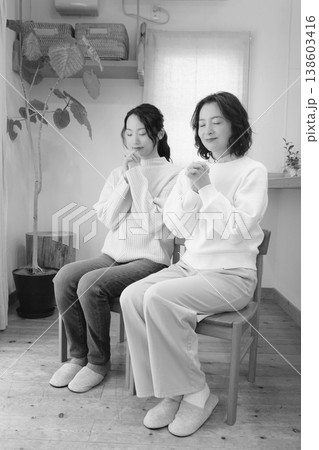 自宅で故人に祈りを捧げる母と娘(モノクロ) 自宅で故人に祈りを捧げる母と娘(モノクロ) 138603416
