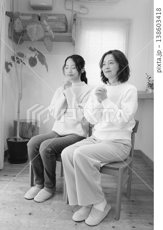 自宅で故人に祈りを捧げる母と娘（モノクロ） 138603418