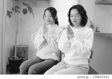 自宅で故人に祈りを捧げる母と娘(モノクロ) 自宅で故人に祈りを捧げる母と娘(モノクロ) 138603432