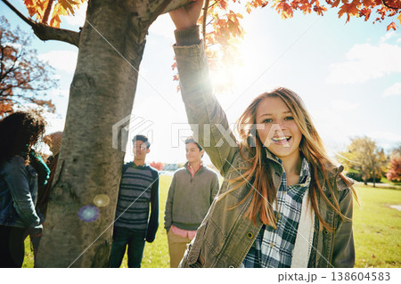 Happy teen girl in nature with friends, park and autumn, sunshine with wellness and portrait. Youth relax outdoor, enjoy fresh air and bonding with smile, lens flare with adventure or travel 138604583