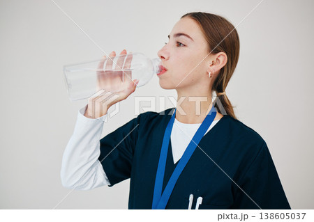 Nurse, woman drinking water in bottle and health, wellness or body nutrition in studio isolated on white background in hospital. Medical professional, hydration and liquid of thirsty surgeon on break Nurse, woman drinking water in bottle and health, wellness or body nutrition in studio isolated on white background in hospital. Medical professional, hydration and liquid of thirsty surgeon on break 138605037