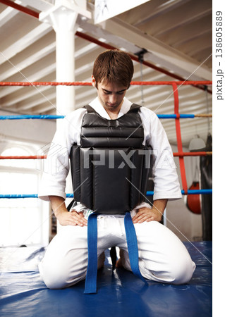 Karate, man and kneeling, exercise with fight in ring and martial arts, protection vest with prayer and ready for battle. Fitness, warrior and muay thai, training and challenge in gym for taekwondo Karate, man and kneeling, exercise with fight in ring and martial arts, protection vest with prayer and ready for battle. Fitness, warrior and muay thai, training and challenge in gym for taekwondo 138605889