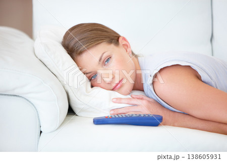 Sad, relax and a woman watching tv on a sofa in the living room of her home for entertainment. Face, depression and remote with a young person streaming a video, movie or film in her apartment Sad, relax and a woman watching tv on a sofa in the living room of her home for entertainment. Face, depression and remote with a young person streaming a video, movie or film in her apartment 138605931