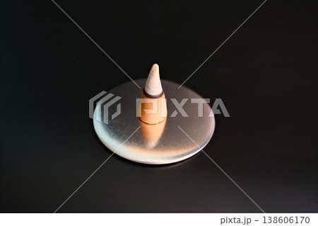 Burning incense sandalwood cone on plate on black background 138606170
