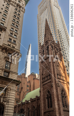 New york, usa august 14,2024. Fifth avenue presbyterian church spire rising against glass and steel skyscrapers under a clear blue midtown manhattan sky 138606261