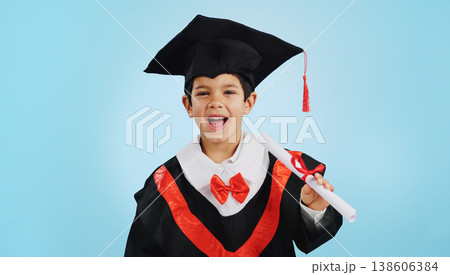 Graduate, child and celebration with portrait and happiness in studio on blue background for education. Development, kid and success with excited expression, diploma or certificate for achievement 138606384