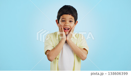 Smile, kid and hands on face for surprise in studio isolated on a blue background mockup space. Portrait, wow and happy child shocked at good news, promo announcement and excited facial expression Smile, kid and hands on face for surprise in studio isolated on a blue background mockup space. Portrait, wow and happy child shocked at good news, promo announcement and excited facial expression 138606399
