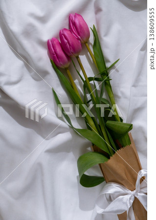 Bouquet of pink tulips in craft eco-friendly paper bag on messy bed. Romantic morning scene. Greeting card Holiday flowers springtime 138609555