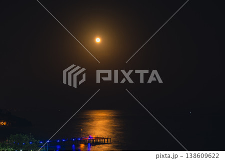 Moonlight Over Sea Waves Full Moon Glow ocean waves on sandy beach at night wooden pier. The moon illuminates water surface. Concept of beach vacation slowing down on seacoast Moonlight Over Sea Waves Full Moon Glow ocean waves on sandy beach at night wooden pier. The moon illuminates water surface. Concept of beach vacation slowing down on seacoast 138609622