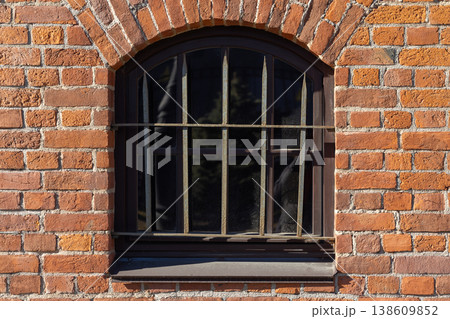 An arched, barred window in red brick wall, close up photo An arched, barred window in red brick wall, close up photo 138609852
