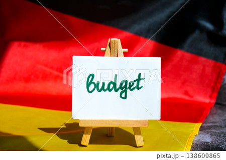 Paper note with words BUDGET on National symbol of Germany. German wave silky flag background. Economy federal annual finance planning Paper note with words BUDGET on National symbol of Germany. German wave silky flag background. Economy federal annual finance planning 138609865