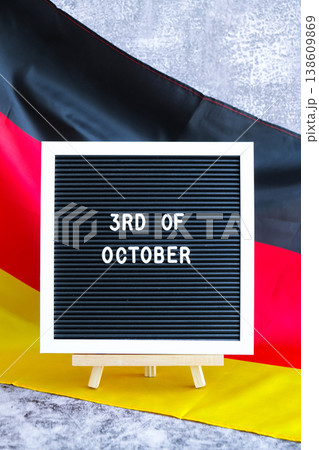 Letter board with message 3rd OF OCTOBER Unity day National symbol of Germany. German wave silky flag background. Historical remembrance and public holiday 138609869