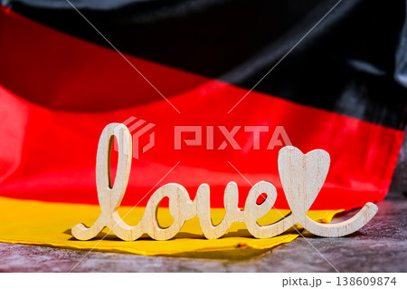 Wooden word love on National symbol of Germany. German full framed wave Germany fabric flag background. Copy space for your text. Independence Wooden word love on National symbol of Germany. German full framed wave Germany fabric flag background. Copy space for your text. Independence 138609874