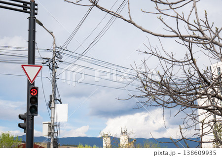 Red arrow traffic light against a cloudy sky with dense electrical wires and urban infrastructure Red arrow traffic light against a cloudy sky with dense electrical wires and urban infrastructure 138609935
