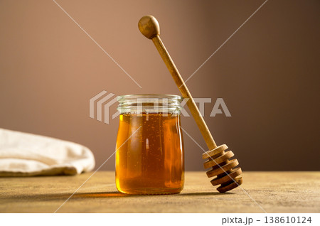 Jar of honey with wooden dipper, sweet liquid, neutral background Jar of honey with wooden dipper, sweet liquid, neutral background 138610124