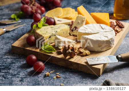 Cheese board, different types of cheese on a board, served with honey, nuts, grapes and dried fruits. 138610127