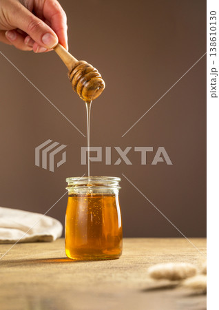 Jar of honey with wooden dipper, sweet liquid, neutral background Jar of honey with wooden dipper, sweet liquid, neutral background 138610130