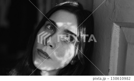 Black and white portrait of young woman with dramatic window light 138610982