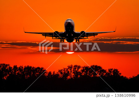 Passenger airliner landing against the backdrop crimson sunset 138610996