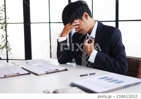 Businessman experiencing stress at work due to heavy workloads, financial worries, and the pressure of responsibility. Businessman experiencing stress at work due to heavy workloads, financial worries, and the pressure of responsibility. 138611012