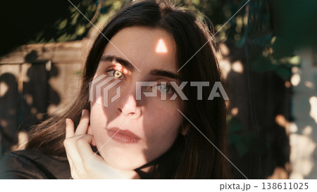 Young woman portrait with dappled sunlight outdoors 138611025
