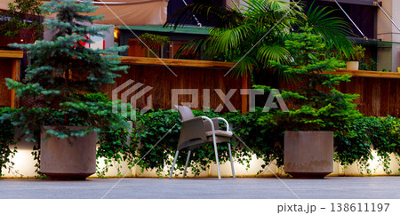 Modern outdoor seating area with lush greenery and ambient lighting 138611197