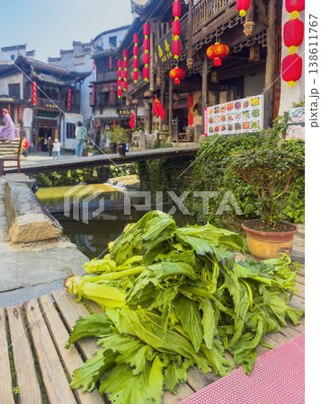 Fresh mustard greens rest on wooden planks beside a canal 138611767
