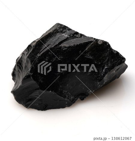 Polished Black Obsidian Volcanic Glass Stone Fragment with Sharp Edges and Glossy Texture on White Background. 138612067