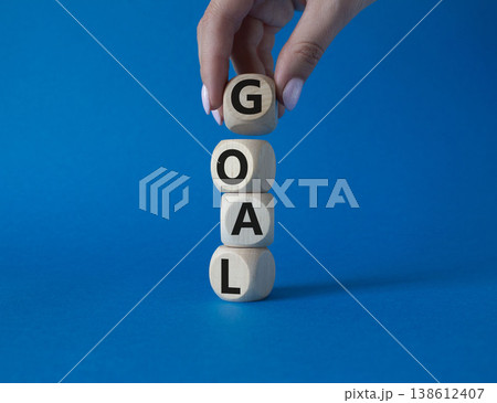 Goal symbol. Concept word Goal on wooden cubes. Beautiful blue background. Businessman hand. Business and Goal concept. Copy space. Goal symbol. Concept word Goal on wooden cubes. Beautiful blue background. Businessman hand. Business and Goal concept. Copy space. 138612407