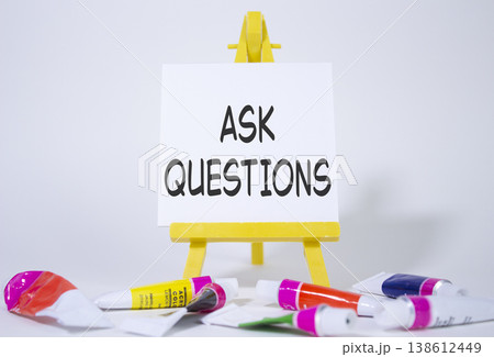 Ask Questions symbol. Wooden blocks with words Ask Questions. Beautiful white background with paints and easel. Business and Ask Questions concept. Copy space. 138612449