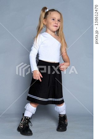 little girl strikes a playful pose with her fists raised near her chin during a studio shoot. Her fun, carefree expression and trendy outfit capture the essence of childhood joy and energy. little girl strikes a playful pose with her fists raised near her chin during a studio shoot. Her fun, carefree expression and trendy outfit capture the essence of childhood joy and energy. 138612470