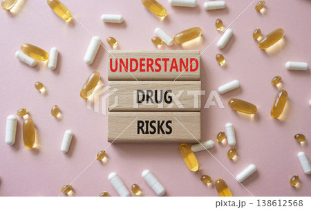 UNDERSTAND DRUG RISKS symbol. Concept words UNDERSTAND DRUG RISKS on wooden blocks. Beautiful pink background with pills. Healthcare and UNDERSTAND DRUG RISKS concept. Copy space. 138612568