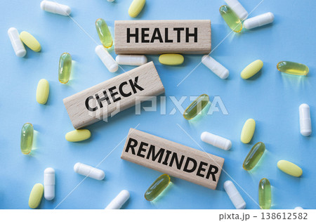 Health check reminder symbol. Concept words Health check reminder on wooden blocks. Beautiful pink background with pills. Healthcare and Health check reminder concept. Copy space. 138612582