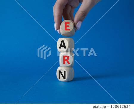 Earn symbol. Concept word Earn on wooden cubes. Businessman hand. Beautiful blue background. Business and Earn concept. Copy space. Earn symbol. Concept word Earn on wooden cubes. Businessman hand. Beautiful blue background. Business and Earn concept. Copy space. 138612624