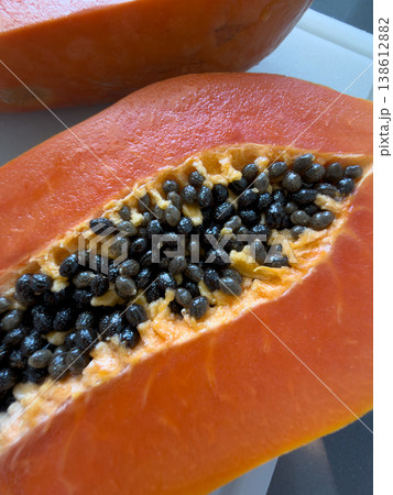 A ripe papaya lies on a cutting board in close-up 138612882