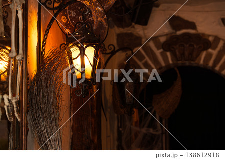 Spooky Halloween decorations with lantern and broom on wall near stone archway at night 138612918
