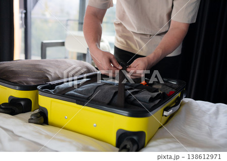 Young man packing suitcase on bed at home before travel Young man packing suitcase on bed at home before travel 138612971