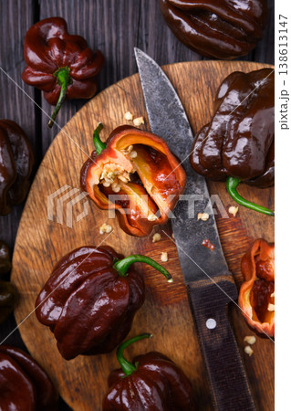 Chocolate habanero peppers with knife and cut halves on wooden board 138613147