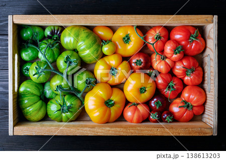 Wooden crate filled with mixed heirloom tomatoes top view Wooden crate filled with mixed heirloom tomatoes top view 138613203
