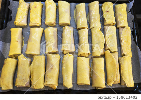 Top-Down View of Many Meat-Filled Crepe Rolls Arranged on a Baking Tray 138613402