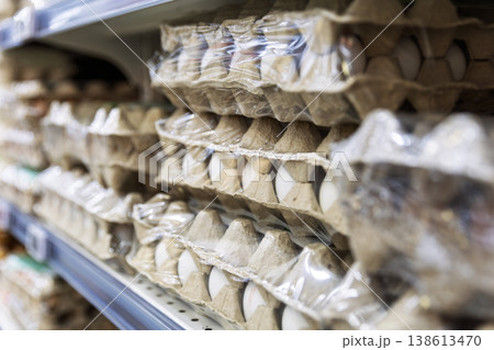Chicken egg cartons in protective plastic wrap on supermarket shelves Chicken egg cartons in protective plastic wrap on supermarket shelves 138613470