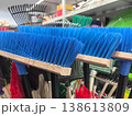 Brightly colored brooms line the shelves of a vibrant cleaning supply store 138613809