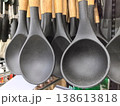 Stylish black cooking spoons with wooden handles hanging in a store 138613818
