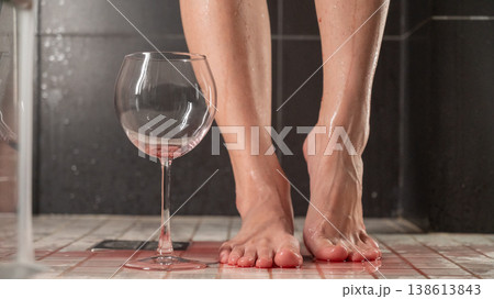 Foot fetish. A woman pours wine from a glass onto her feet in the shower. Foot fetish. A woman pours wine from a glass onto her feet in the shower. 138613843