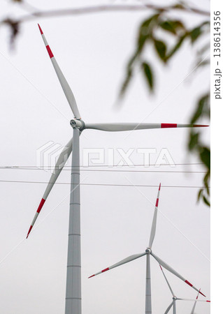 wind turbines in field rotate their blades to generate energy. windmill on spacious green field. 138614356