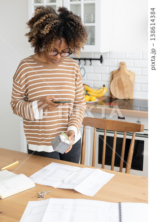 female architect or realtor holds mock up of house in her hands and photographs it for client.  138614384