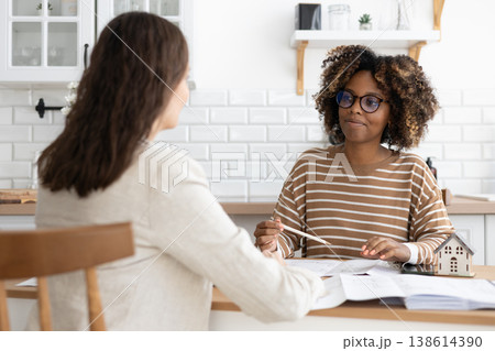confident curly haired woman with curly dark hair, designer or realtor, shows mock up house. confident curly haired woman with curly dark hair, designer or realtor, shows mock up house. 138614390