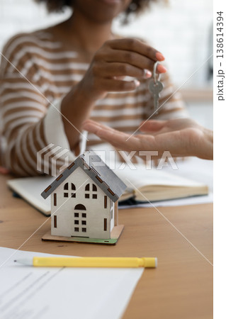 Close-up of happy woman realtor or property owner handing over key to house. Close-up of happy woman realtor or property owner handing over key to house. 138614394