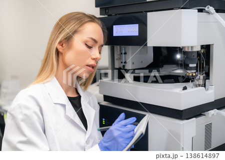 A specialist documents findings from advanced measurement instrument at biochemical analysis workstation. 138614897