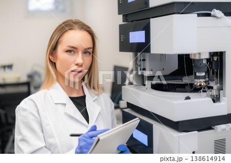 Analytical technician recording data while operating a high performance liquid chromatography system in a clinical laboratory. Analytical technician recording data while operating a high performance liquid chromatography system in a clinical laboratory. 138614914